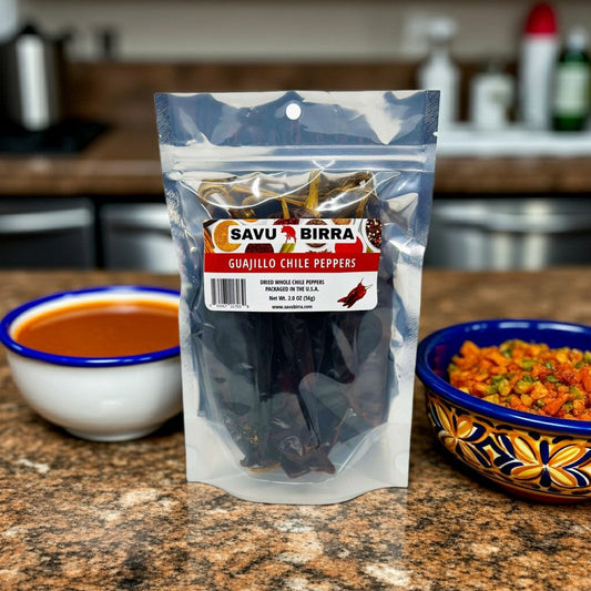 Savu Birra whole dried guajillo chile peppers in a pouch beside bowls of sauce and chopped ingredients.